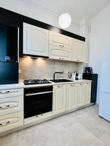 a kitchen with white cabinets and a stove top oven at Altheda Living Topaz 29C-14 in Sfîntu Ilie