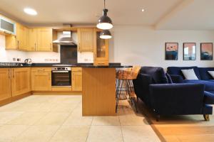 eine Küche mit Holzschränken und eine Bar mit blauen Stühlen in der Unterkunft APARTMENT BY THE BEACH, courtyard garden in Saint Merryn