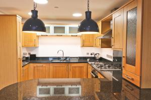 eine Küche mit Holzschränken und schwarzen Arbeitsplatten in der Unterkunft APARTMENT BY THE BEACH, courtyard garden in Saint Merryn + 11 Fotos