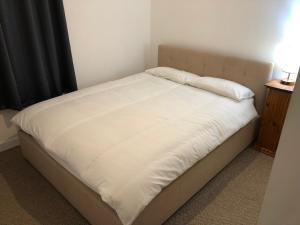 een bed met witte lakens en kussens erop bij Cosy flat, Scalloway in Scalloway