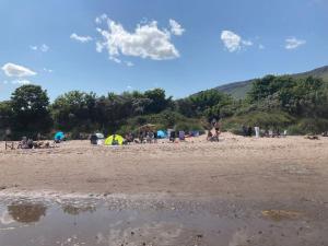 a group of people on a beach with tents at RedBayBeach-House in Glenariff