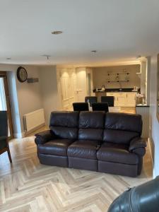a living room with a leather couch and a kitchen at RedBayBeach-House in Glenariff