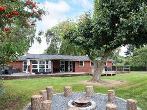 une maison rouge avec un arbre dans la cour dans l'établissement 10 person holiday home in Juelsminde, à Juelsminde