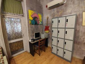 een kamer met een bureau met een computer en een gitaar bij Rooster Hostel in Veliko Tŭrnovo