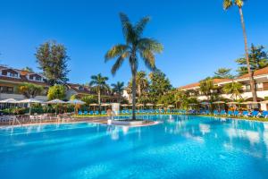 a large pool at a resort with palm trees and chairs at Parque San Antonio in Puerto de la Cruz