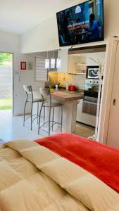 1 dormitorio con 1 cama y cocina con TV en Great and Full Suite in Carlos Paz w/ heated pool en Villa Carlos Paz