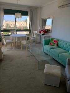 ein Wohnzimmer mit einem grünen Sofa und einem Tisch in der Unterkunft Casas Holiday - Golf Campoamor in Orihuela