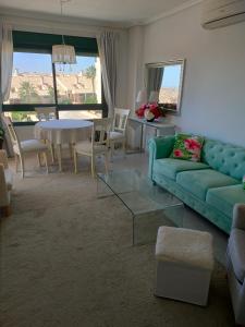 a living room with a green couch and a table at Casas Holiday - Golf Campoamor in Orihuela Costa