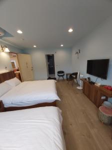 um quarto de hotel com duas camas e uma televisão de ecrã plano em 旅途中海邊民宿 em Sanzhi