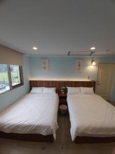 two beds in a room with white sheets at 旅途中海邊民宿 in Sanzhi
