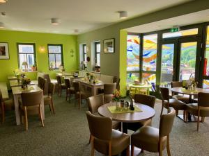 un restaurante con mesas, sillas y paredes verdes en Villa Frieden Hotel & Seminarhaus, en Bad Blankenburg