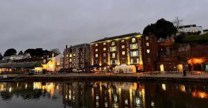 a building next to a body of water at night at Clocktower Suite in Exeter