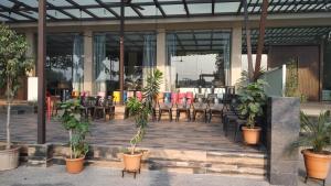a patio with tables and chairs and potted plants at Hotel Ruturaj Regency in Dhule