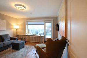 ein Wohnzimmer mit einem Sofa, Stühlen und einem Fenster in der Unterkunft Strandhaus 4,  App. Strandresidenz in Westerland