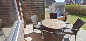 einen Holztisch und Stühle auf einer Terrasse in der Unterkunft Strandhaus 4,  App. Strandresidenz in Westerland