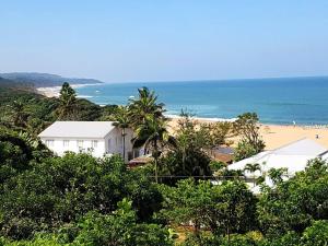 a beach with a white building and the ocean at Magnificent beach house with stunning ocean views! in Zinkwazi Beach