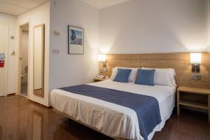 a bedroom with a large bed with blue pillows at Hotel Villa San Juan in San Juan de Alicante +44 photos