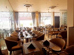 a restaurant with tables and chairs and a large window at Hotel Ruturaj Regency in Dhule