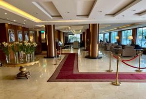 a lobby with tables and chairs and flowers in a building at Rose Park Riyadh in Riyadh
