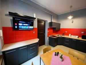 a kitchen with a table and a kitchen with red tiles at Hostel Rynek22 in Gliwice