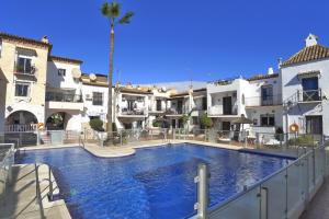 a large swimming pool in a courtyard with buildings at Casa Andaluz in Nerja