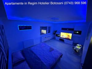a blue room with a bed and a tv at Apartament cu 2 camere/Curte privata/La parter/Lux oferim factura in Botoşani