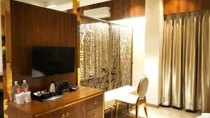 a room with a television and a desk with a chair at Hotel Ruturaj Regency in Dhule