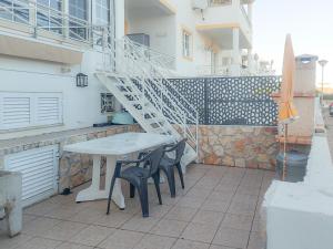 une table et des chaises blanches sur une terrasse avec un escalier dans l'établissement Casa da Praia - São Rafael - BY BEDZY, à Albufeira