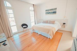 a white bedroom with a bed and a wooden floor at La Olivia Hotel Boutique & Spa in La Falda