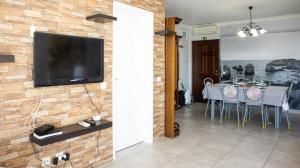 un salon avec une télévision sur un mur en briques dans l'établissement Casa da Praia - São Rafael - BY BEDZY, à Albufeira