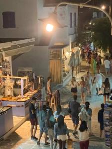 un grupo de personas caminando por un mercado por la noche en La Main Street suite, en Antíparos