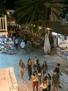 un grupo de personas caminando por la calle por la noche en La Main Street suite, en Antíparos