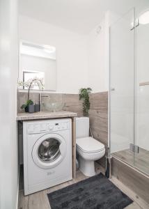 a bathroom with a washing machine and a toilet at Central Apartments Grzybowska in Warsaw