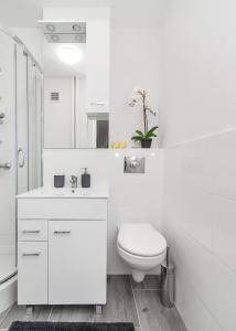 a white bathroom with a toilet and a sink at Central Apartments Grzybowska in Warsaw