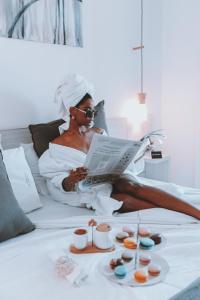 una mujer acostada en una cama leyendo un libro en La Olivia Hotel Boutique & Spa en La Falda