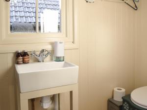 uma casa de banho com um lavatório branco e uma janela em Molly The Shepherds Hut em Bampton