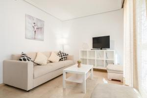 Biały salon z kanapą i telewizorem w obiekcie Green- Apartments Las Setas w Sewilli