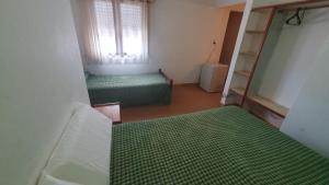 a room with two green beds and a window at Habitacion economica con estacionamiento Necochea in Necochea