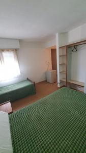 a room with two green beds and a window at Habitacion economica con estacionamiento Necochea in Necochea