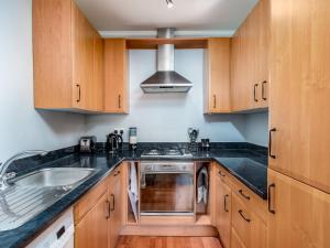 a kitchen with wooden cabinets and a sink and a stove at Pass the Keys Stylish Cosy and Central 1 Bed Flat with Parking in Rickmansworth
