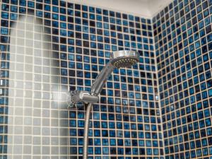 a shower in a bathroom with blue tiles at Pass the Keys Stylish Cosy and Central 1 Bed Flat with Parking in Rickmansworth