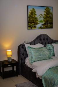 Ce lit se trouve dans un dortoir doté d'une lampe sur une table. dans l'établissement Appartement cosy blue bonapriso, à Douala