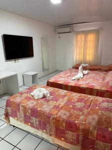 a hotel room with two beds and a flat screen tv at Hotel Pousada Villa Marina in Fortaleza