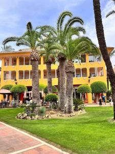grupa palm przed żółtym budynkiem w obiekcie Aquamarine apartment in Marina Sotogrande w mieście Sotogrande