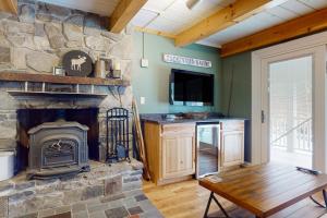 a living room with a stone fireplace and a tv at Deer Run Retreat in Gilford