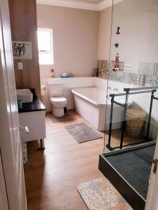 a bathroom with a bath tub and a toilet at 501 Beach Club in Mossel Bay