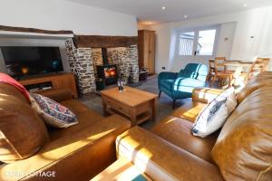 sala de estar con sofá de cuero y chimenea en Cobb Cottage - HiddenDevon, en Winkleigh