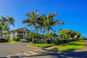 a street with palm trees in front of a house at Poipu Mermaid 912 in Koloa