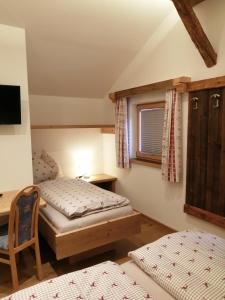 een slaapkamer met 2 bedden, een bureau en een raam bij Hintergugg in Mittersill