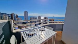 balkon z białym stołem i kieliszkami do wina w obiekcie En el centro de Benidorm y con vistas al mar w mieście Benidorm